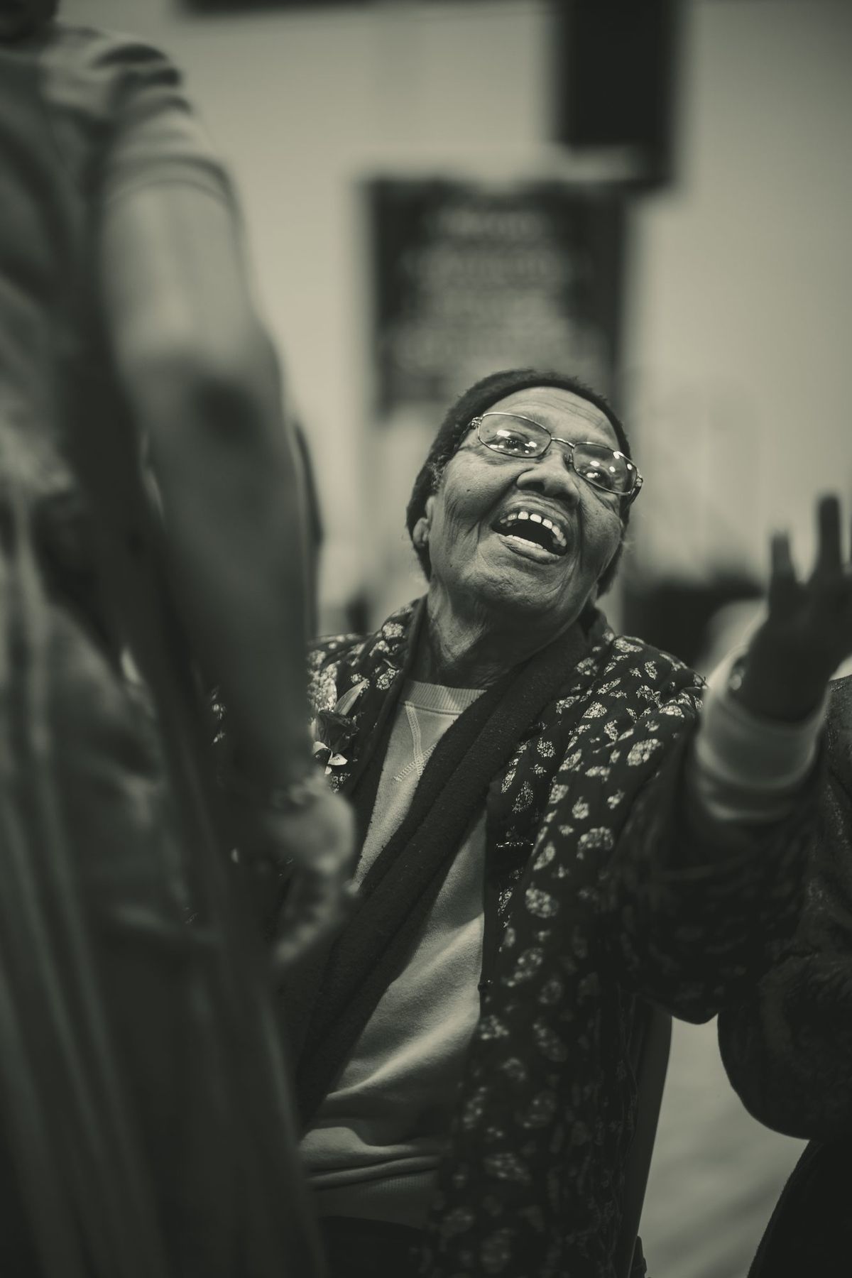 An elder laughing with her hand raised